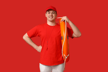 Wall Mural - Male lifeguard with ring buoy and whistle on red background