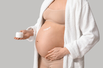 Wall Mural - Young pregnant woman with cream against stretch marks against grey background, closeup