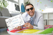© Pixel-Shot - Happy male office worker in sunglasses on inflatable ring holding sign with text OUT OF OFFICE. Summer vacation concept
