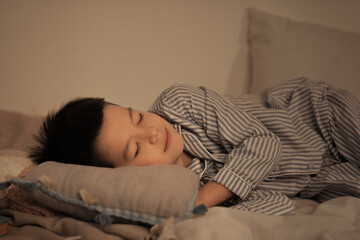 Poster - Cute little Asian boy in pajamas sleeping in bed