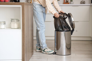 Wall Mural - Woman taking garbage bag from trash bin in kitchen