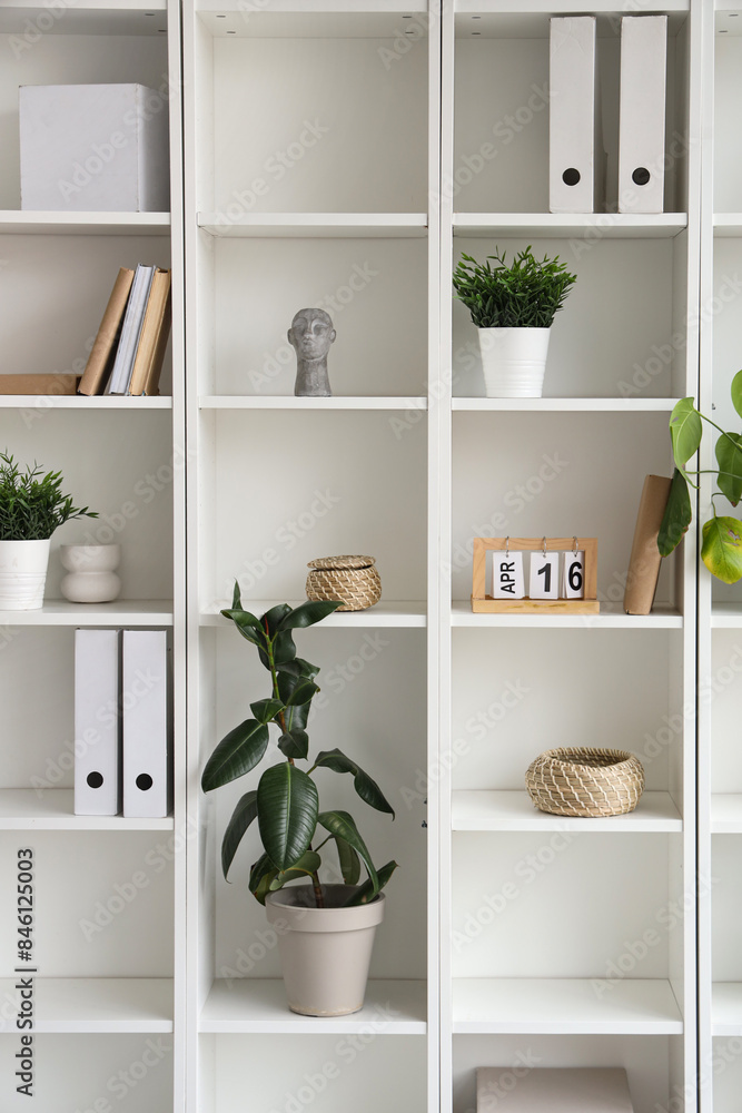 Shelf unit with plants and folders in room