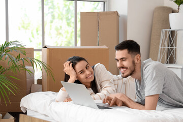 Wall Mural - Young couple using laptop in bedroom on moving day