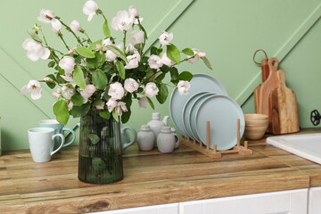 Wall Mural - Vase with blossoming branches and utensils on counter in kitchen