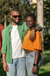 © DimaBerlin - Carefree pleased african american couple students standing outdoor smiling hugging looking at camera with good mood. Happy black friends guy girl with embrace enjoy time together on meeting in park.