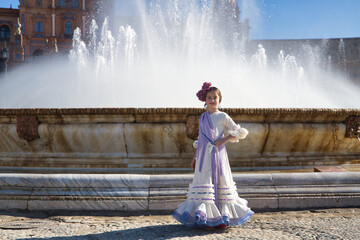 Wall Mural - Girl dancing flamenco, posing looking at camera, in typical flamenco costume next to spectacular fountain in a beautiful square in Seville. Dance concept, flamenco, typical Spanish, Seville, Spain.