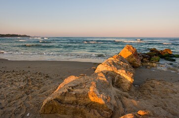 Wall Mural - Mediterranean coast. Sea surf with white foam of waves. Morning sunrise on the coast of Israel, rocks, sea sand and water.