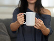© Javed - Closeup of female hands with a mug of beverage. A girl in grey t-shirt holding white mug in hand. Mug for PSD mockup. Cropped close-up image of a coffee