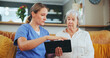 © Azeemud/peopleimages.com - Senior woman, nurse and consulting with tablet for healthcare, medicare or results at nursing home. Female person or caregiver talking to mature patient with technology on living room sofa at house