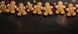 © StockKing - A top view of traditional Christmas gingerbread men cookies being decorated on a dark table creating a festive copy space image for the Xmas time background