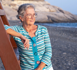 Sticker - Attractive senior woman looking at the golden sunset at sea enjoying free time, vacation or retirement