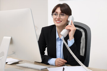 Canvas Print - Smiling secretary talking on telephone at table in office