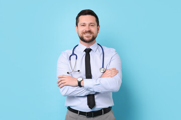 Canvas Print - Smiling doctor with stethoscope on light blue background