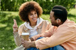 © Bliss - An African American couple communicates through sign language while sitting together in a park.