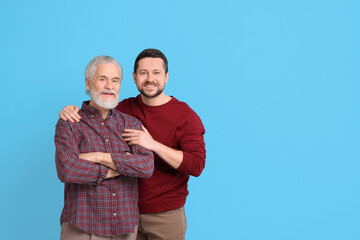 Wall Mural - Happy son and his dad on light blue background, space for text