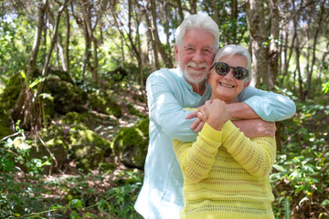 Wall Mural - Happy active senior family couple enjoying mountain hike in the forest appreciating nature and freedom, retired seniors hug expressing love and care