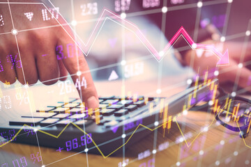 Wall Mural - Close up of male hand using calculator on desk glowing falling forex chart and index grid on blurry background. Crisis, accounting and financial recession concept. Double exposure.