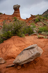 Wall Mural - rock formation in the desert against cloudy sky and green bushbery