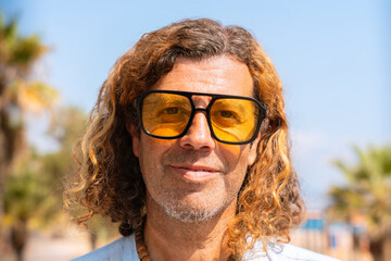 Caucasian adult man wearing smiling sunglasses looking at camera. Man on vacation on the coast.