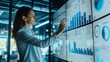 © mashimara - A focused businesswoman reviewing data on a large screen in a modern office, highlighting the importance of analytics in a collaborative professional setting.