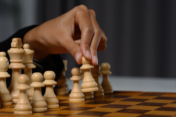 Wall Mural - Businesswoman moving a chess piece on a chess board. Business competition strategy and management concept