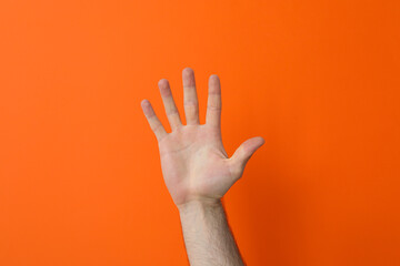 Wall Mural - Male hand showing five fingers on orange background