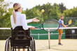 © Robert Kneschke - Woman in wheelchair playing tennis with partner on outdoor court