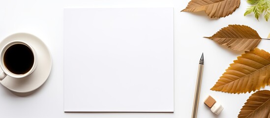 Wall Mural - An office desk viewed from above with items like a notebook, book, supplies, pencil, leaf, and coffee cup arranged neatly on the white surface, forming a visually appealing copy space image.