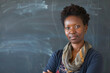 © Victor Bertrand - A poised teacher stands confidently with arms crossed in front of a chalkboard with light chalk sketches, donning a patterned scarf and navy blue cardigan.