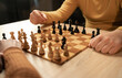 © mtrlin - Close-up of two men playing chess at home, making strategic moves, wooden board, indoor setting