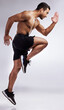 © peopleimages.com - Exercise, body and man running in studio with training for sports competition and performance for wellness goal. Male person, runner and cardio workout with sprint or jump action by white background