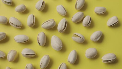 Wall Mural - Pistachios lay on a beautiful sunny yellow background.