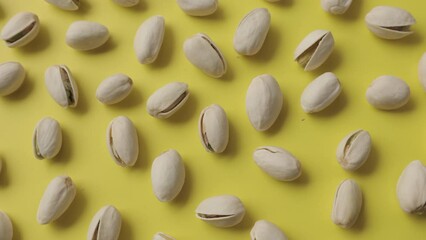 Wall Mural - Pistachios lay on a beautiful sunny yellow background.