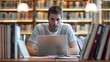 © Thipphaphone - Caucasian Male Student Studying Diligently with Laptop in Modern Library