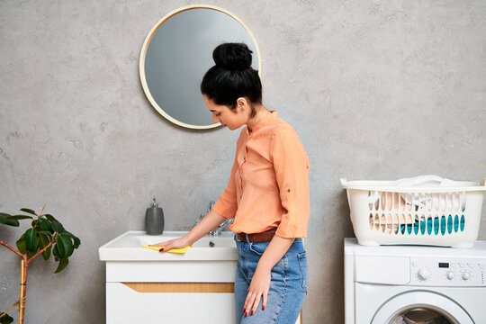a stylish woman in casual attire standing in front of a washing machine, ready to tackle household c