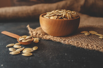 pumpkin seeds in a wooden bowl and vintage scoop. Close up on a black background. copy space for text