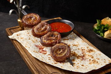 Wall Mural - Grilled Beef and Tail Fat Skewers Rolled Kebabs on Lavash with Red Sauce