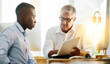 © Donson/peopleimages.com - Male boss, paperwork and employee in office with mentoring, review and discussion at desk. Mature leader, recruitment and explain in workplace with document, contract and assistance while reading
