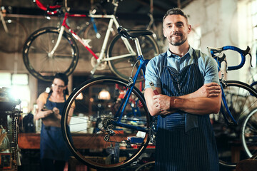 Wall Mural - Mechanic, portrait and arms crossed at work in bicycle repair shop or maintenance garage. Bike, mature handyman and service with professional man for team startup, small business and workshop