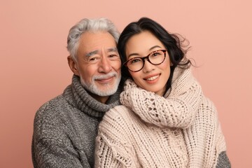 Wall Mural - Portrait of a glad multiethnic couple in their 60s wearing a cozy sweater in front of pastel or soft colors background