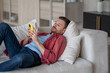 © DimaBerlin - Disinterested man with phone lying on couch surfing online web, procrastination at home. Lazy male with social media addiction on smartphone scrolling internet, enjoy virtual life rest look at screen.