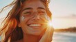 © Prostock-studio - A woman with long, flowing hair smiles as she applies sunscreen to her face while standing on the beach at sunset.