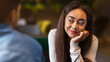 © Prostock-studio - African American girl is sitting at a table in a restaurant, staring intently at a guy who is across from her. The guy seems unaware of her gaze as he eats.