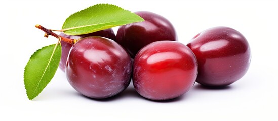 Poster - Close-up view of a cluster of ripe plums with green leaves arranged on a clean white background. with copy space image. Place for adding text or design