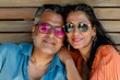 © Markus Schröder - Portrait of a cheerful indian couple in their 40s wearing a trendy sunglasses in light wood minimalistic setup