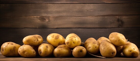 Fototapete - Heap of potatoes on wooden surface with a cutting tool nearby in a rustic setting. with copy space image. Place for adding text or design