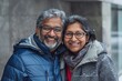 © Markus Schröder - Portrait of a jovial indian couple in their 40s wearing a warm parka isolated on empty modern loft background