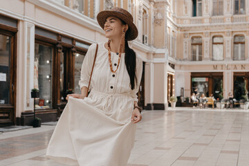 Wall Mural - attractive woman walking in shopping street in Italy on vacation dressed in white summer fashion dress