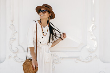 Wall Mural - attractive woman walking in city street on vacation dressed in white summer fashion dress