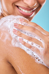 Poster - Woman, soap and shower water cleaning shoulder in studio with female, happy or skincare beauty. Closeup, model and smile of young person in bathroom, wellness and dermatology by blue background